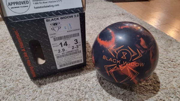 Hammer Black Widow 3.0 bowling ball next to original product box showing specs, premium solid reactive bowling ball for league and tournament use, top-rated performance ball, Amazon review, best bowling ball for heavy oil lanes.